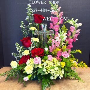 Floral arrangement with red roses, pink stock, yellow and white blooms around a crystal cross centerpiece.